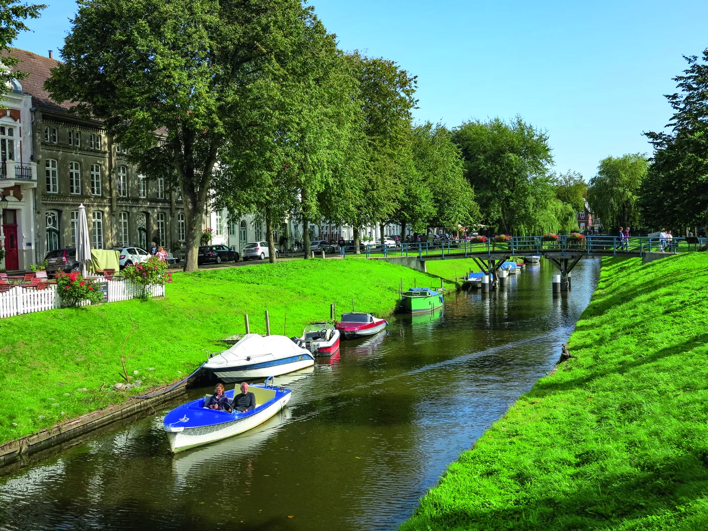 Grachtenartiger Kanal mit Booten und grünen Uferböschungen in Friedrichstadt