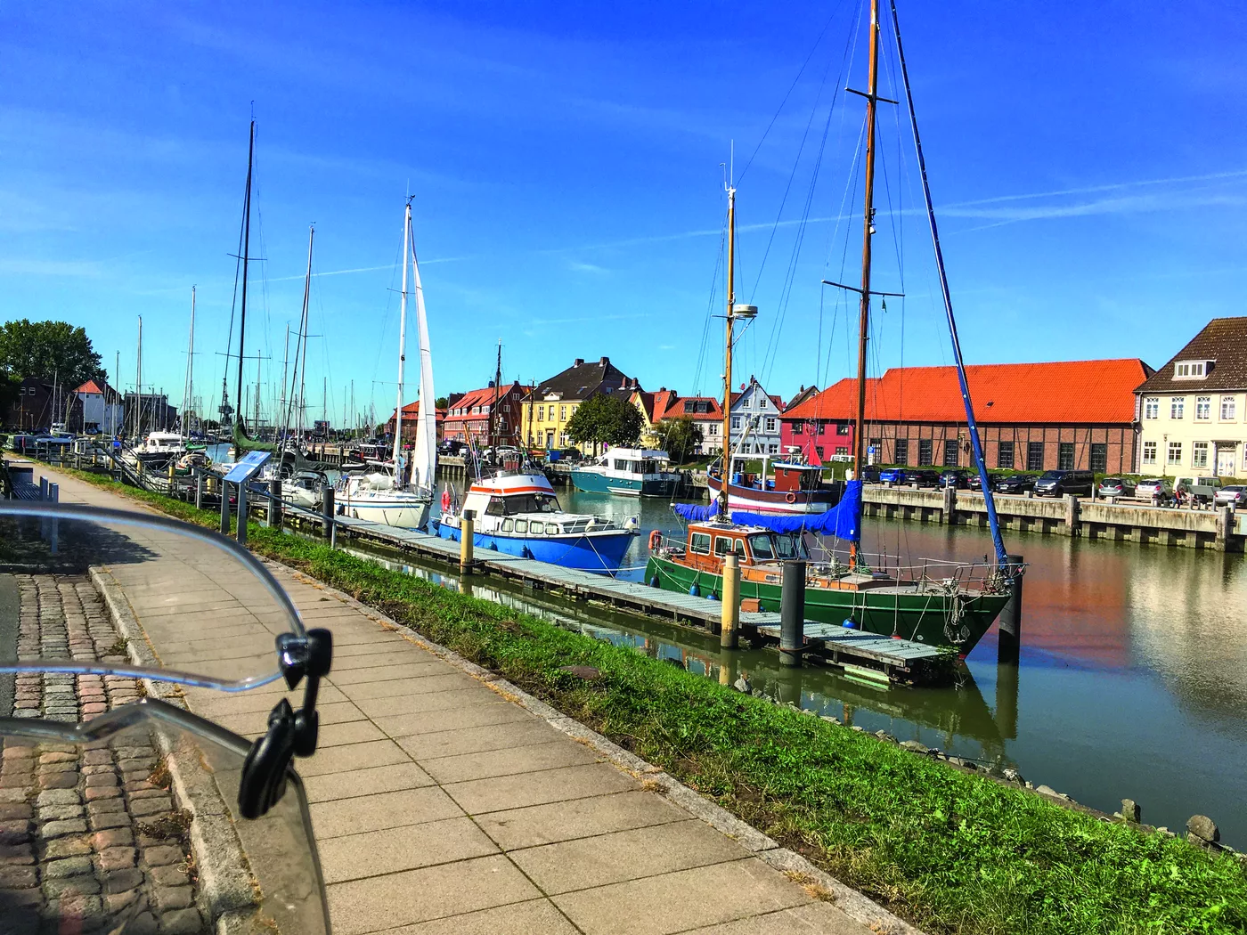 Segelboote im Hafenbecken vor Backsteinhäusern